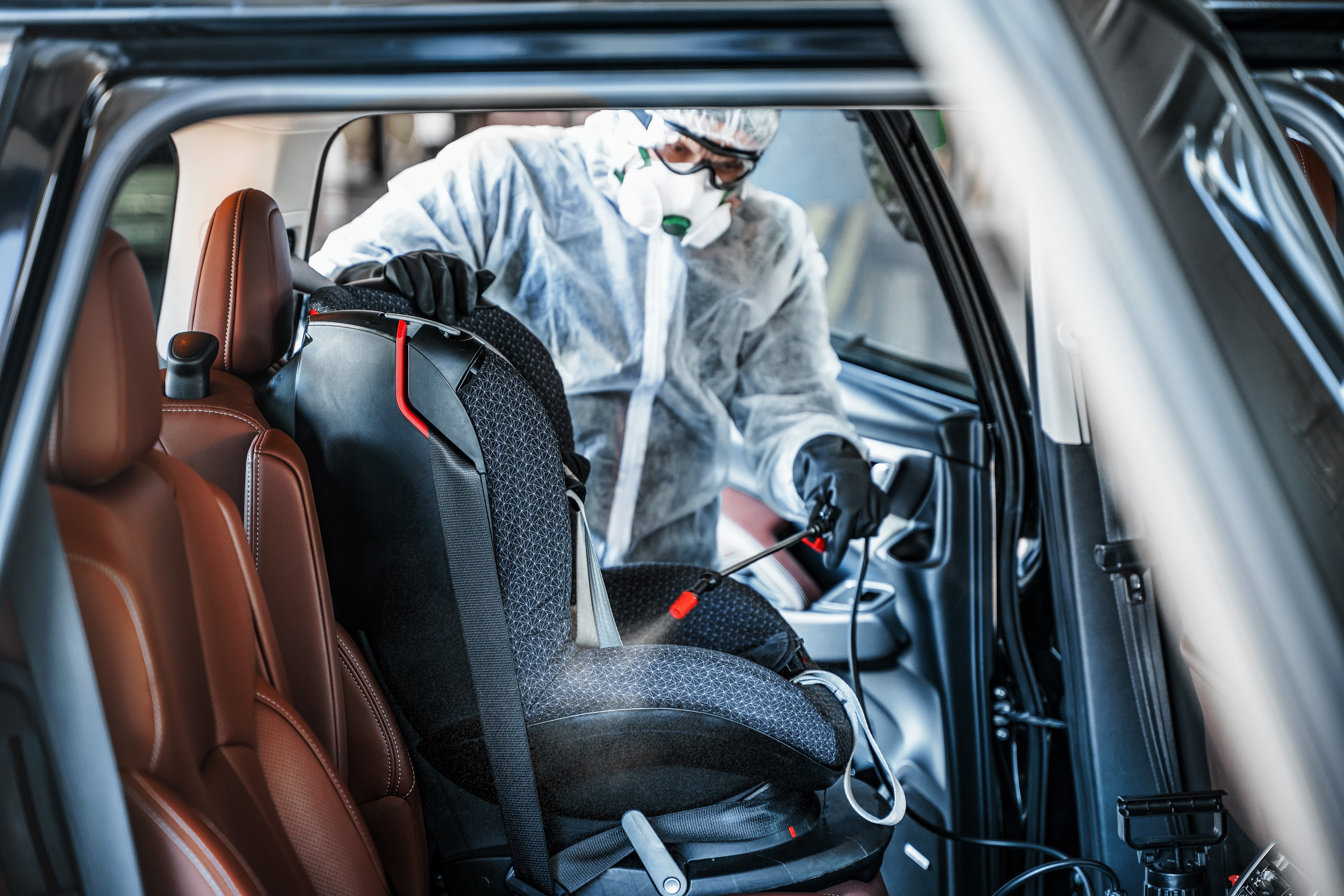 Guy in PPE Spraying Interior of Car at Car Wash